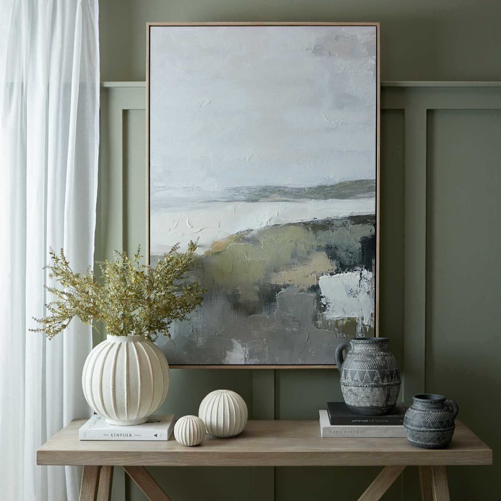 Hillside View hand-painted canvas in a light wood frame above a console table
